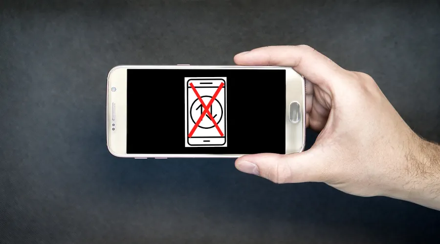 A man holding a mobile phone with a cross sign on mobile data icon